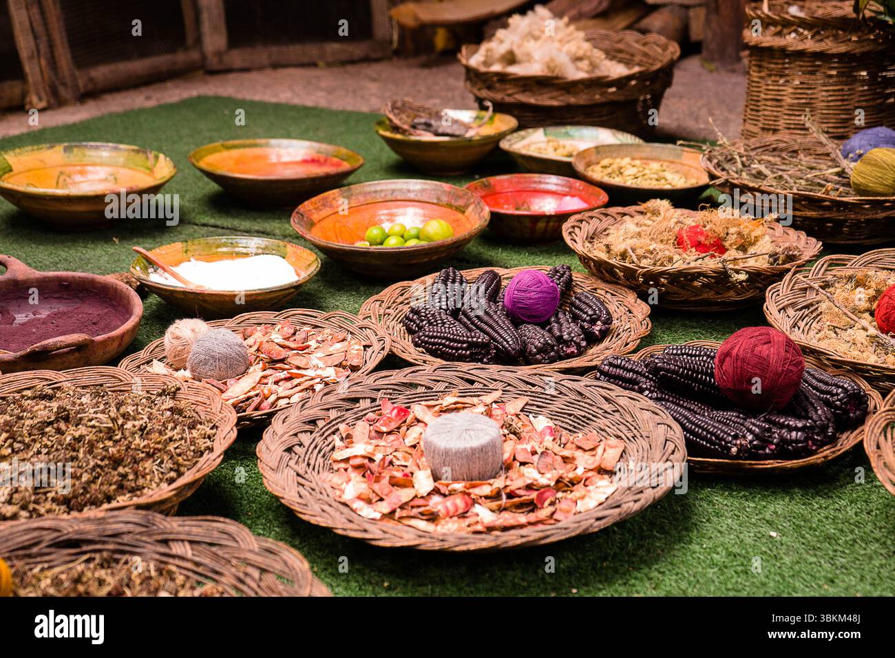 Una colorata disposizione di materiali e coloranti naturali, tra cui filati, semi e ingredienti vegetali, utilizzati per la produzione tessile tradizionale. Foto Stock