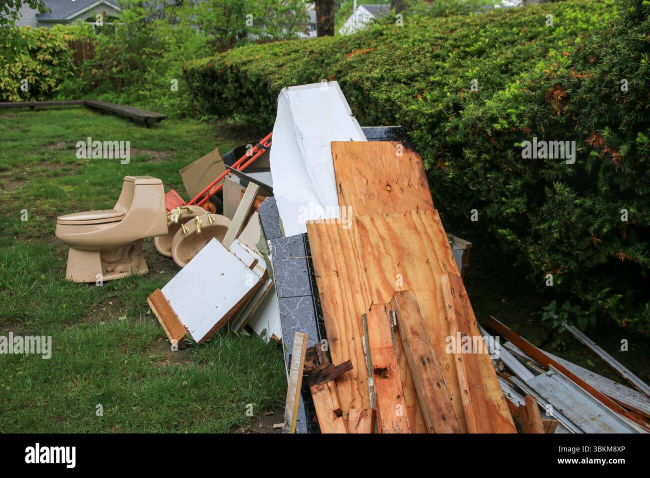 Gli oggetti scartati, tra cui legno, WC e detriti, fanno disordine in un cortile residenziale. Foto Stock