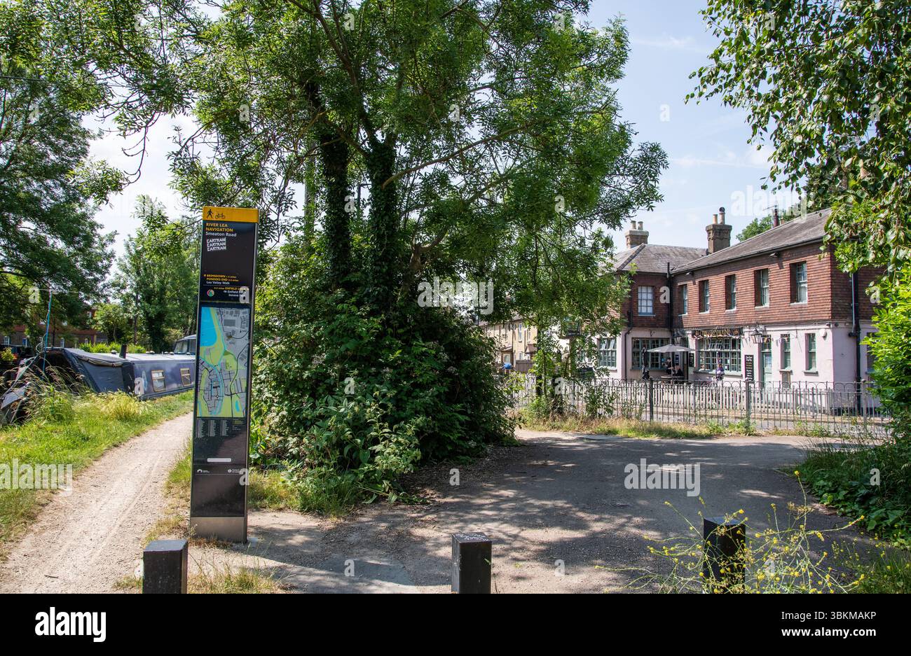 Soleggiata giornata estiva sul sentiero di navigazione del fiume Lea con barche, alberi frondosi e un tradizionale pub britannico in vista, vicino a Enfield Lock, Londra. Foto Stock