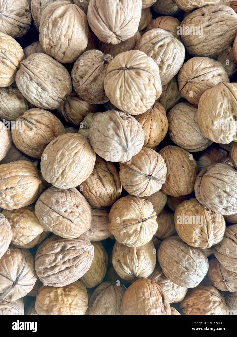Vista ravvicinata di una grande pila di noci non sgusciate. La consistenza ruvida e naturale e i toni della terra creano un'atmosfera rustica e organica, mettendo in risalto il Be Foto Stock