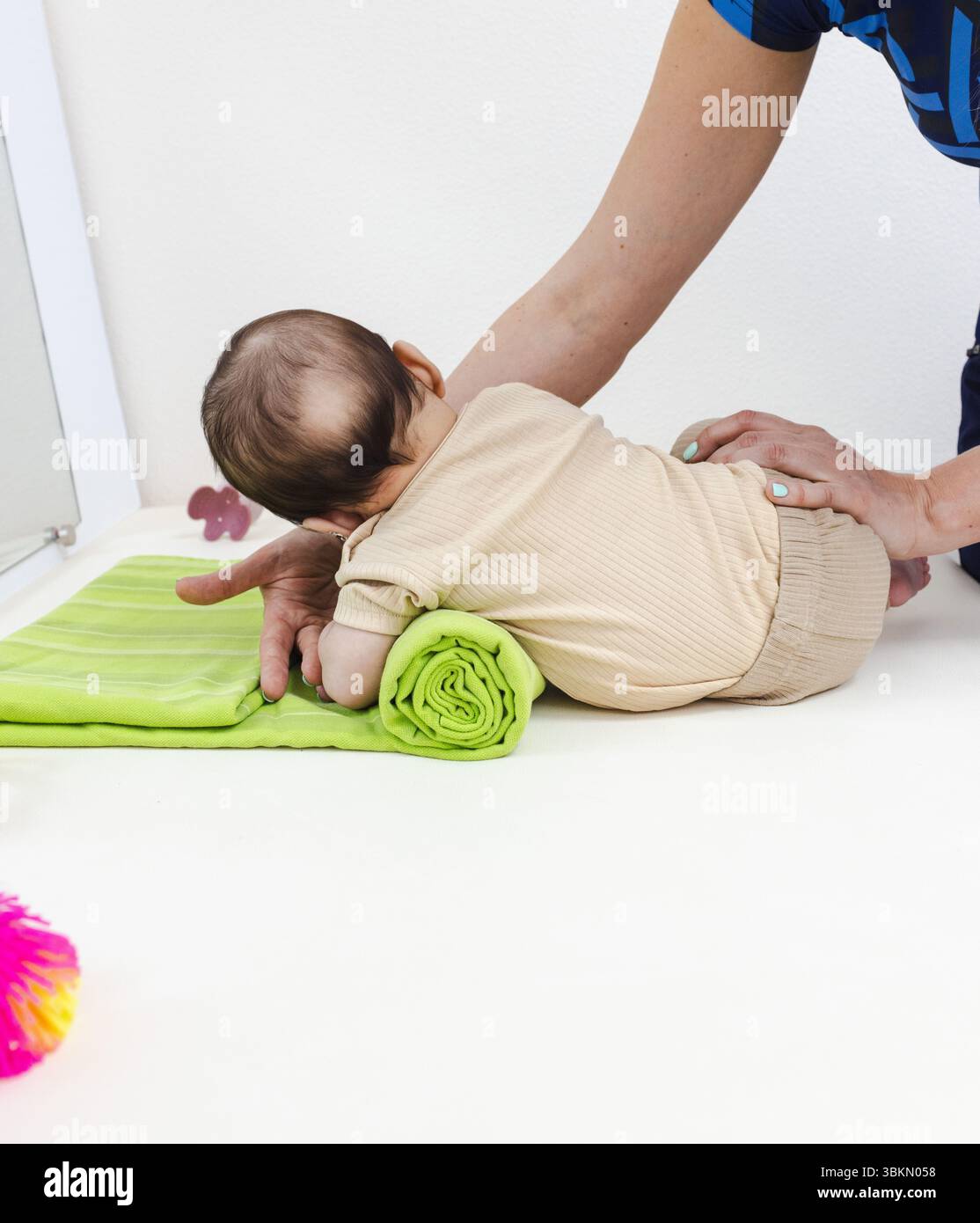 Sessione di fisioterapia con bambino in movimento e posizionamento guidato del braccio. Attività di riabilitazione infantile Foto Stock