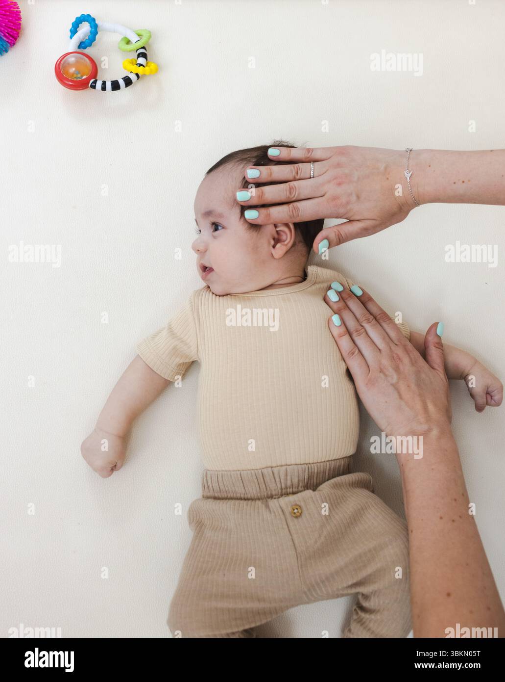 Torcicollo nei neonati. Il fisioterapista esegue un esame per diagnosticare il collo del collo del bambino, esegue esercizi di stretching e cambiamenti nel corpo e nella testa Foto Stock