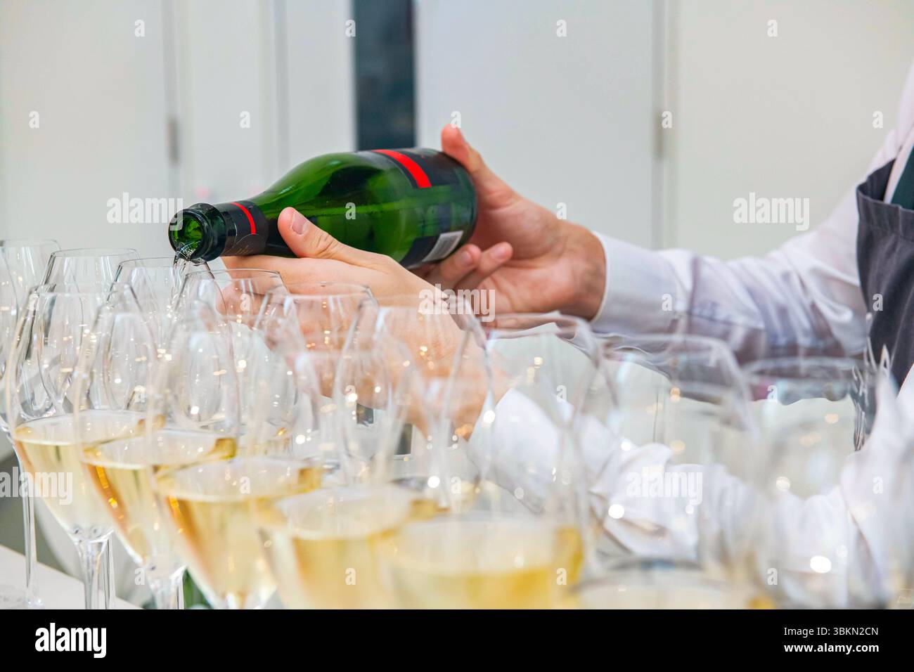 Versare vino frizzante inglese nei bicchieri a una festa Foto Stock