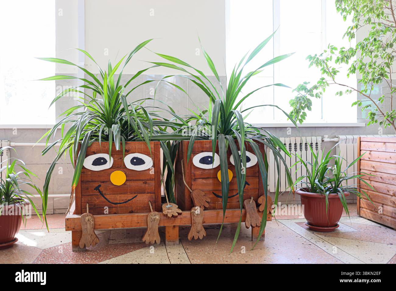 Syzran, Federazione Russa - 11 agosto 2023: Affascinanti piantagioni in legno con volti allegri con vivaci piante verdi, che creano un'atmosfera giocosa in b Foto Stock