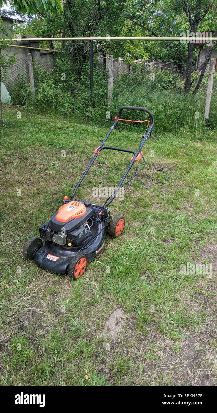 10.05.2025 Moldavia il rasaerba si trova in un giardino verde, pronto per il taglio dell'erba e la manutenzione essenziale Foto Stock