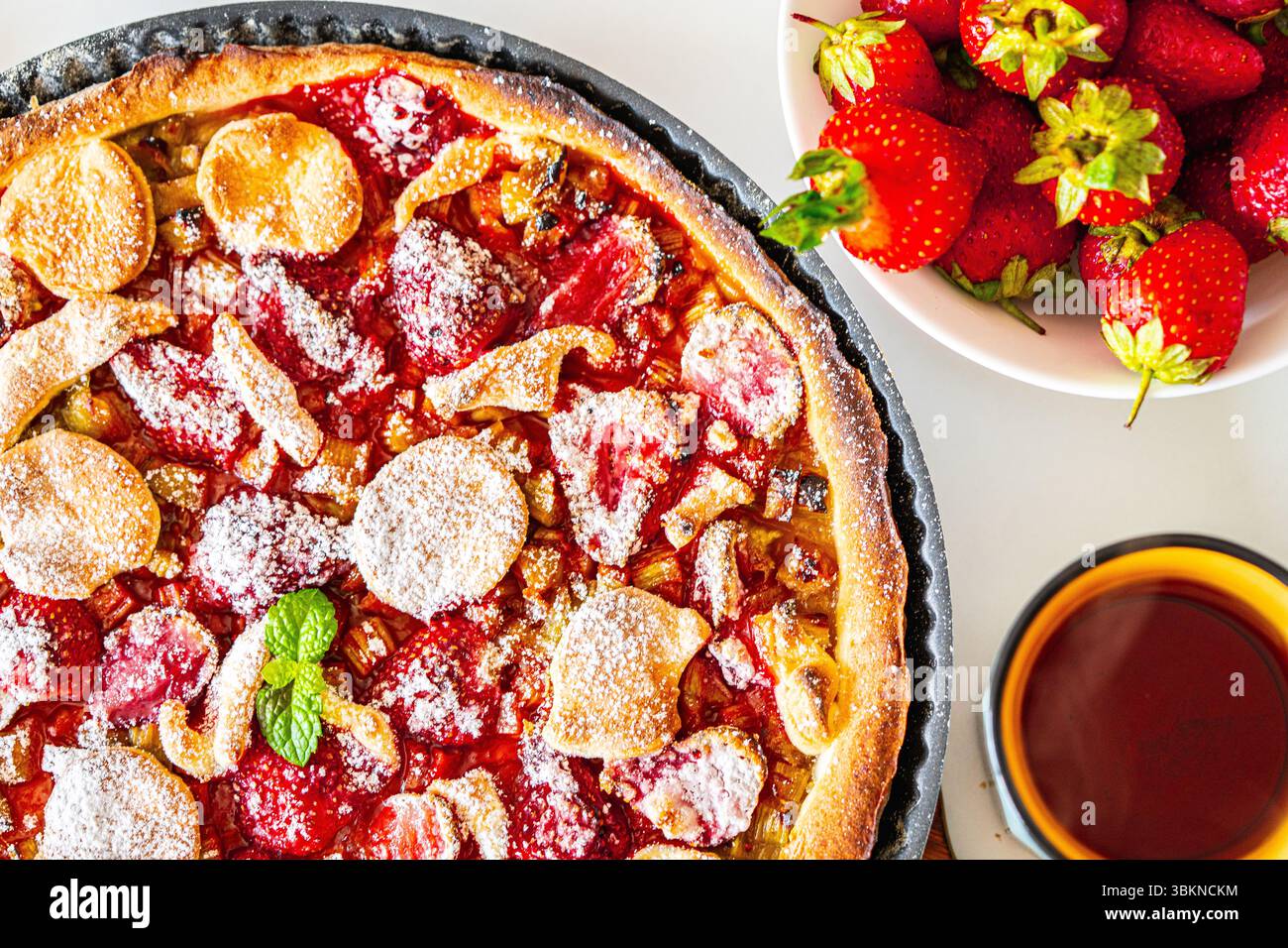 Crostata di rabarbaro con fragole e zucchero su un tavolo bianco. Primo piano. Vista dall'alto. Foto di alta qualità Foto Stock