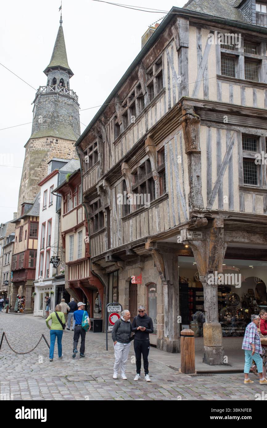 Case in legno con la torre dell'orologio in lontananza, Dinan Foto Stock