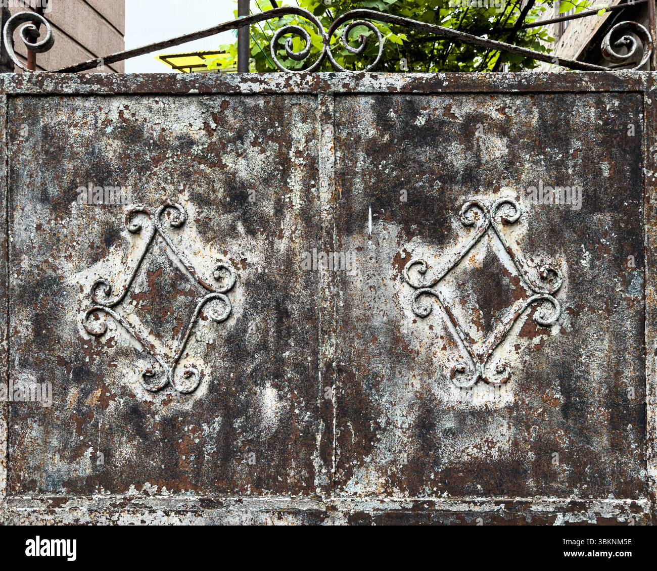 Primo piano di un cancello in ferro battuto arrugginito vintage con design a pergamena ornamentale e superficie in metallo testurizzato. Sfondo grunge. Niente persone. Foto Stock