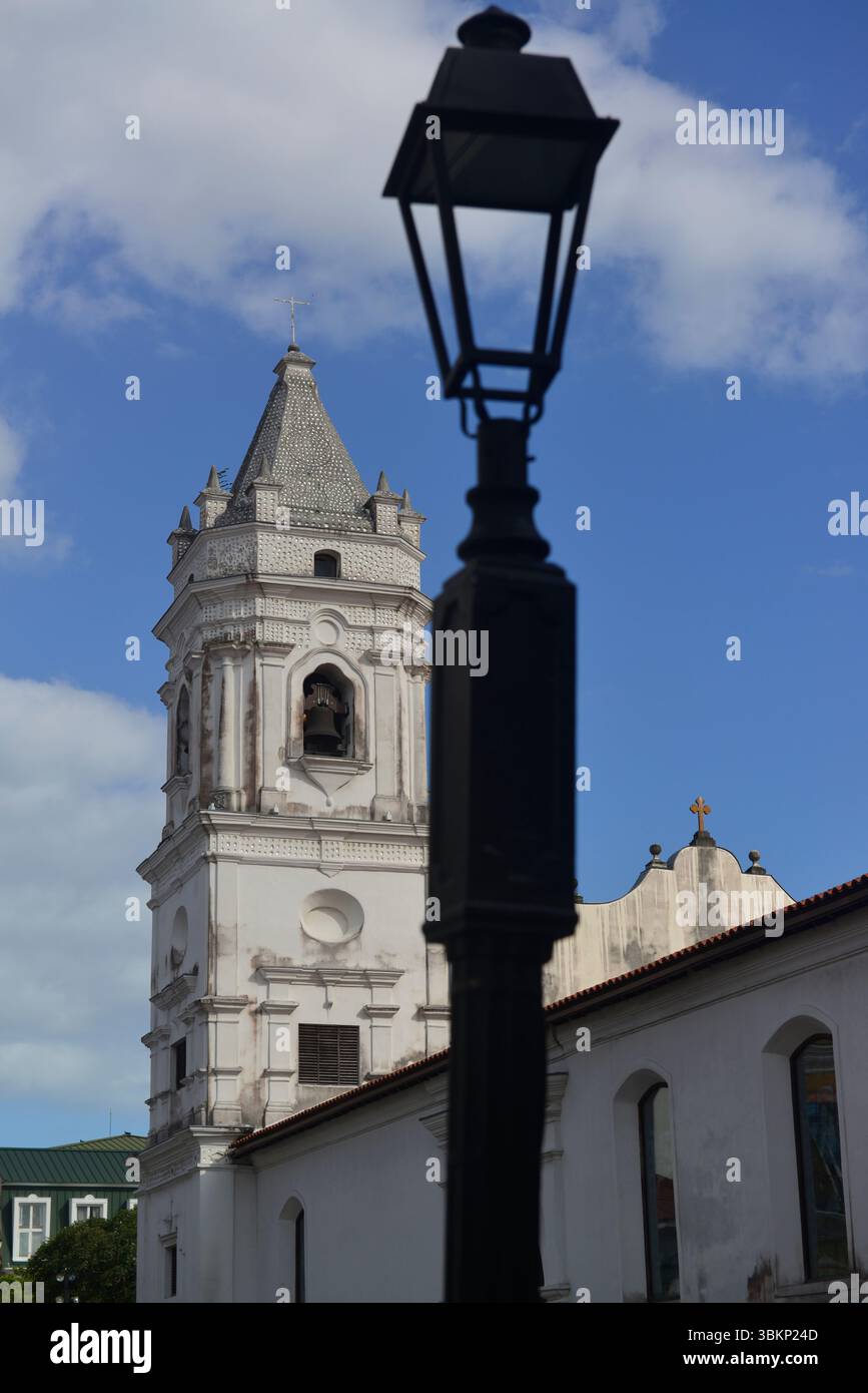Vista di uno dei due campanili della Cattedrale Metroplolitana dietro la silhouette di un classico lampione a casco Viejo, Panama City, Panama. Foto Stock