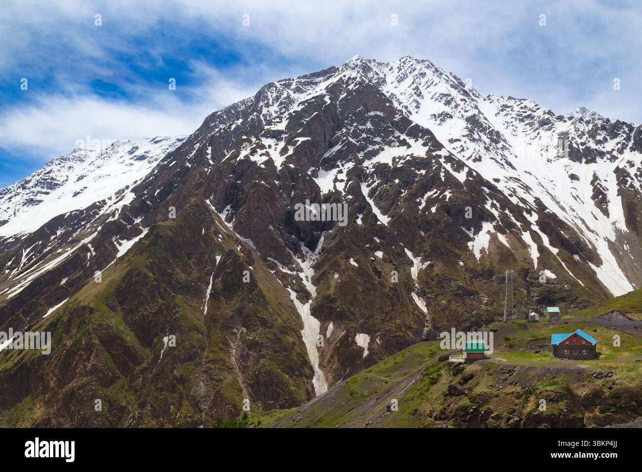 Paesaggio montano in primavera, con piccoli edifici ai piedi della montagna Foto Stock