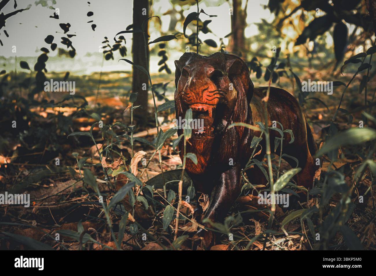 Scultura di leone in legno che ruggisce in una scena boschiva simulata, con la luce del sole che proietta ombre realistiche su foglie e figure, mescolando arte e natura. Foto Stock