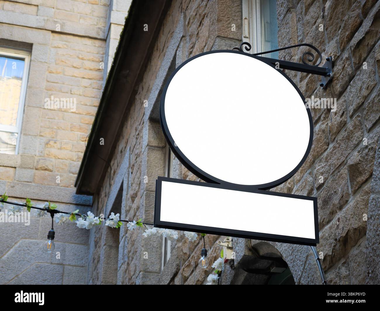 Mockup di cartelli editabili su un muro di pietra con pannelli rotondi e rettangolari. Vista stradale angolata ideale per la presentazione di marchi o logo in urban conte Foto Stock