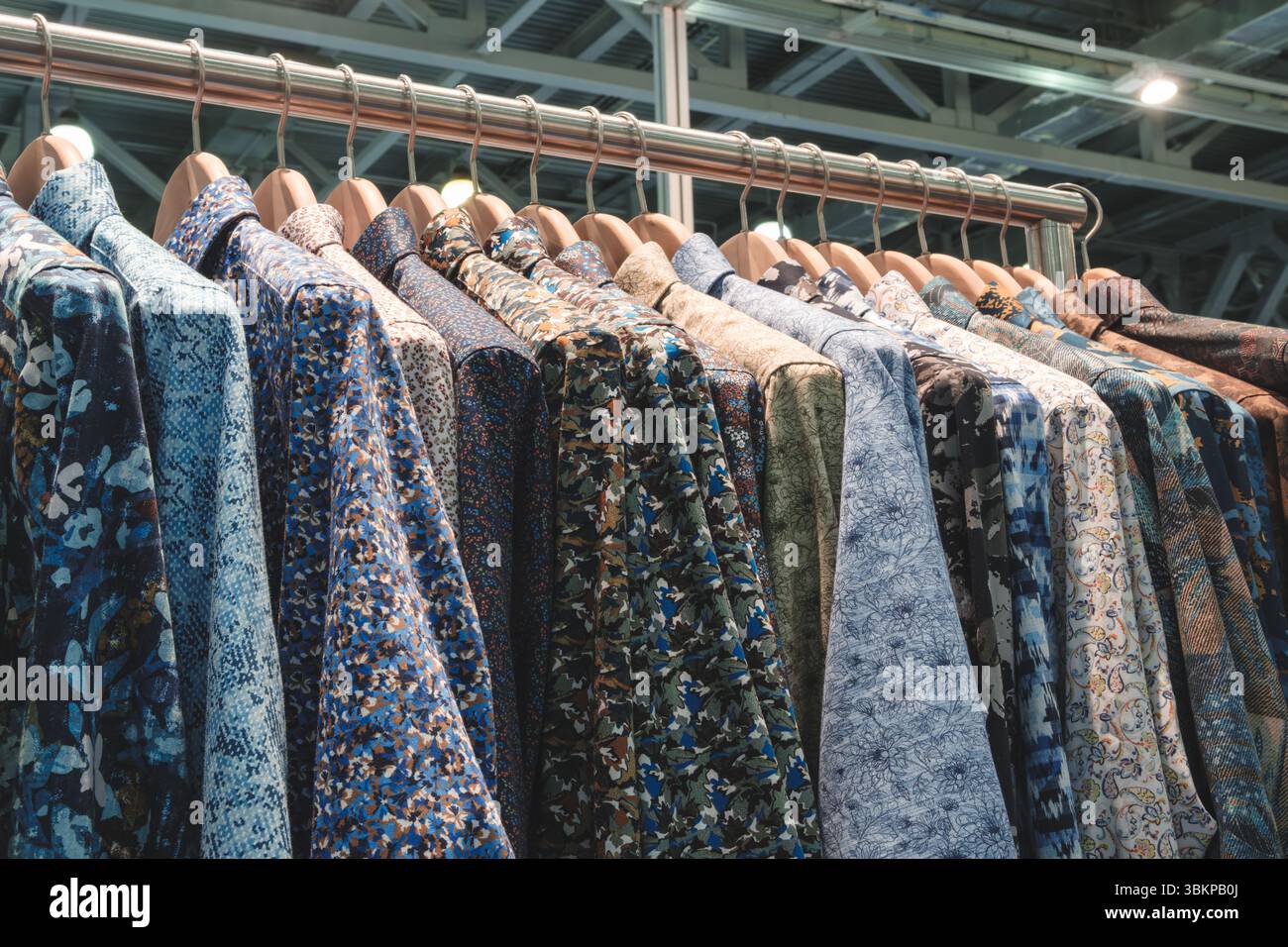 Scaffale di vestiti con una camicia blu appesa alla sommità. Gli indumenti sono appesi su un rack e sono di colori diversi Foto Stock