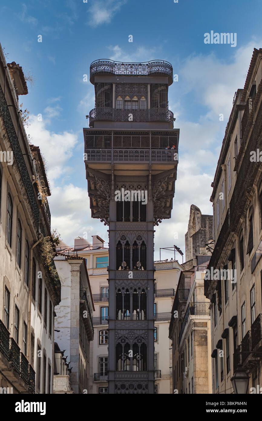 L'iconico ascensore di Santa Justa a Lisbona, in Portogallo, sorge tra edifici storici sotto un cielo blu brillante, perfetto per viaggi, architettura e ispirazione per il paesaggio urbano. Foto Stock