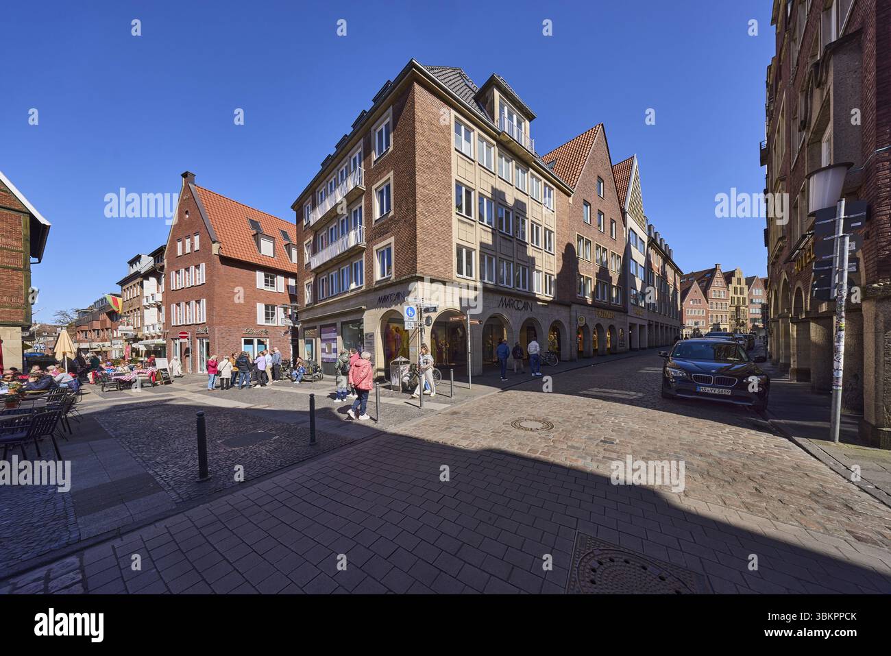 Centro città, zona pedonale, architettura generale, edifici in mattoni, parcheggio con veicoli, pedoni come motivo secondario, cielo blu senza nuvole, i Foto Stock