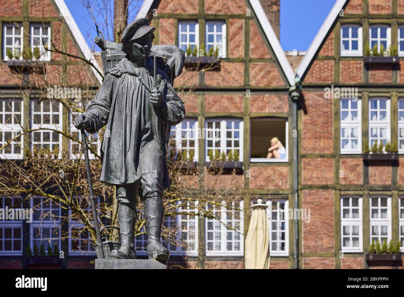 Monumento di Kiepenkerl, scultura in bronzo, architettura in mattoni, facciata, finestra, profondità di campo, cielo azzurro senza nuvole, Spiekerhof, Muenster, Muensterland, ind Foto Stock