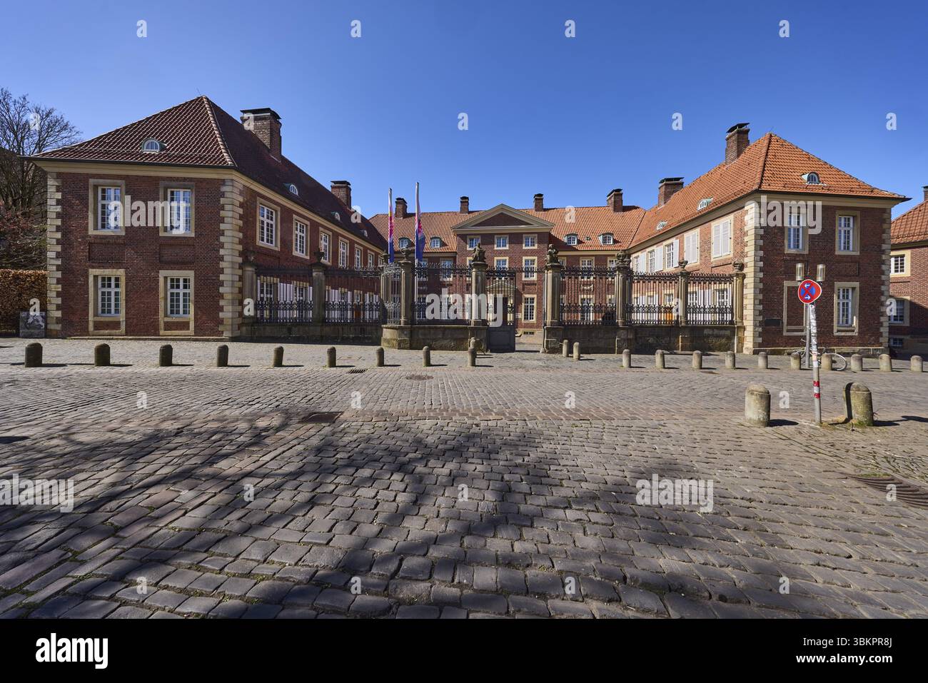 Vicariato generale episcopale, vicariato, costruzione di mattoni, dissuasori, pavimentazione in ciottoli, cielo azzurro senza nuvole, piazza della cattedrale, Muenster, Muensterland, Foto Stock