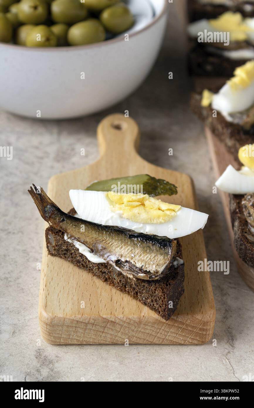 Panino con sardina, uovo, cetriolo sottaceto su una tavola di legno, tavolo Foto Stock