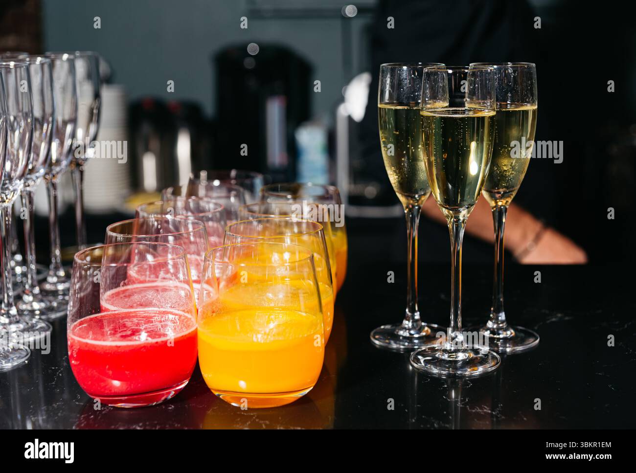 Bicchieri di succo d'arancia e rosso accompagnati da flute di champagne ripieni di spumante, preparati per una festa o una festa. Foto Stock
