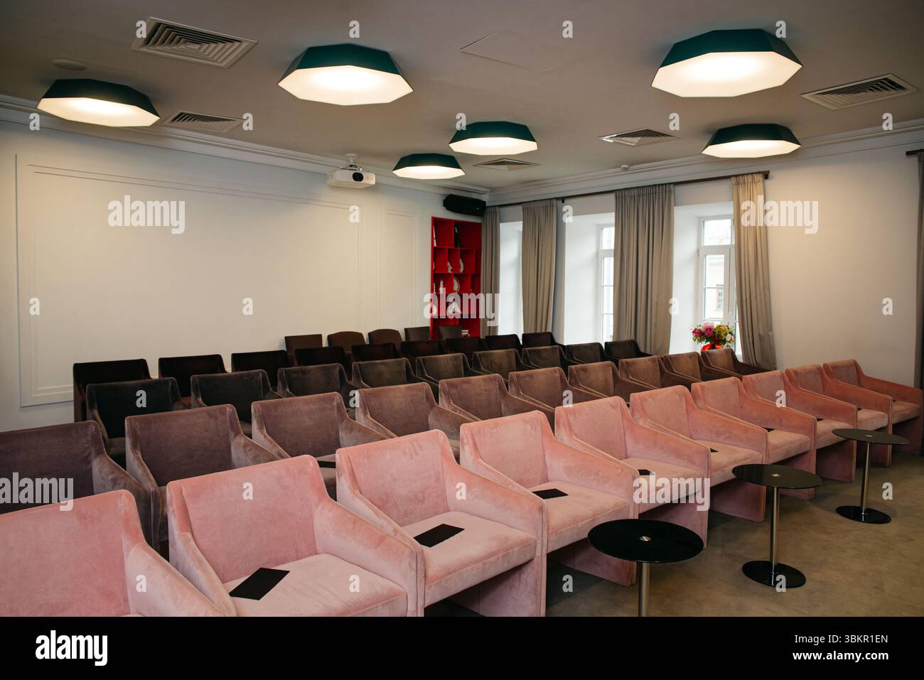 Elegante sala per conferenze o seminari dotata di morbide sedie in velluto in fila con tavolini, pronta per un evento d'affari o educativo. Foto Stock