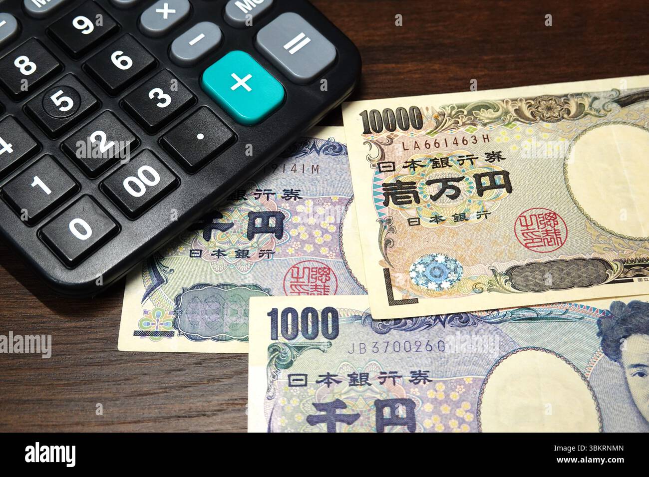 Cina. 22 giugno 2025. In questa illustrazione fotografica, una calcolatrice nera si sovrappone alle banconote giapponesi da 1.000 - yen e 10.000 - yen su un tavolo di legno. business, economia, valuta, contanti, bolletta, bollette, soldi, banconote, 10000 yen, banconote, giapponesi, yen, finanza, diecimila, esempio, tastiera, laptop credito: SOPA Images Limited/Alamy Live News Foto Stock