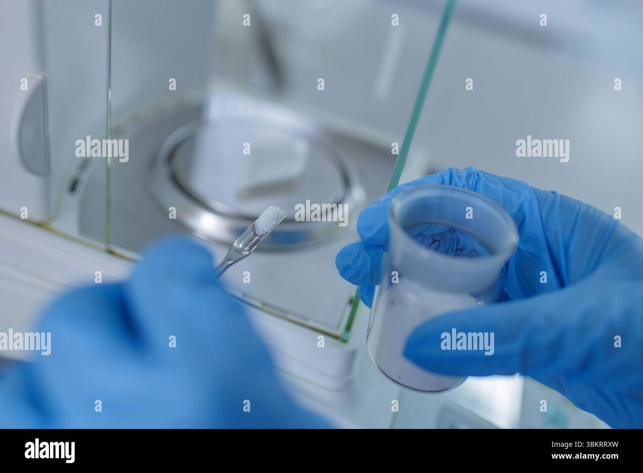 Scienziato con guanti che pesa polvere chimica su bilancia analitica in moderni laboratori per la ricerca e l'analisi farmaceutica Foto Stock
