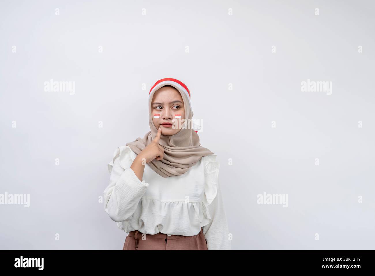 Ritratto di bella giovane donna musulmana asiatica celebrare il giorno dell'indipendenza indonesiana cercando seriamente di pensare alla domanda e guardando lo spazio di copia Foto Stock