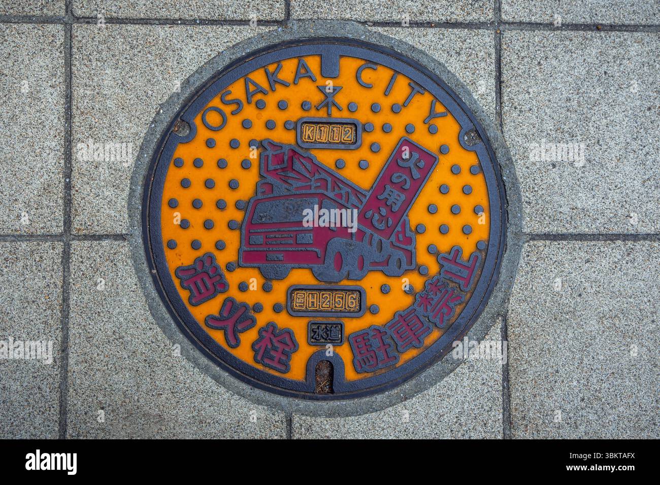 Un tombino idrante che presenta un camion rosso dei pompieri nella città di Osaka, in Giappone Foto Stock