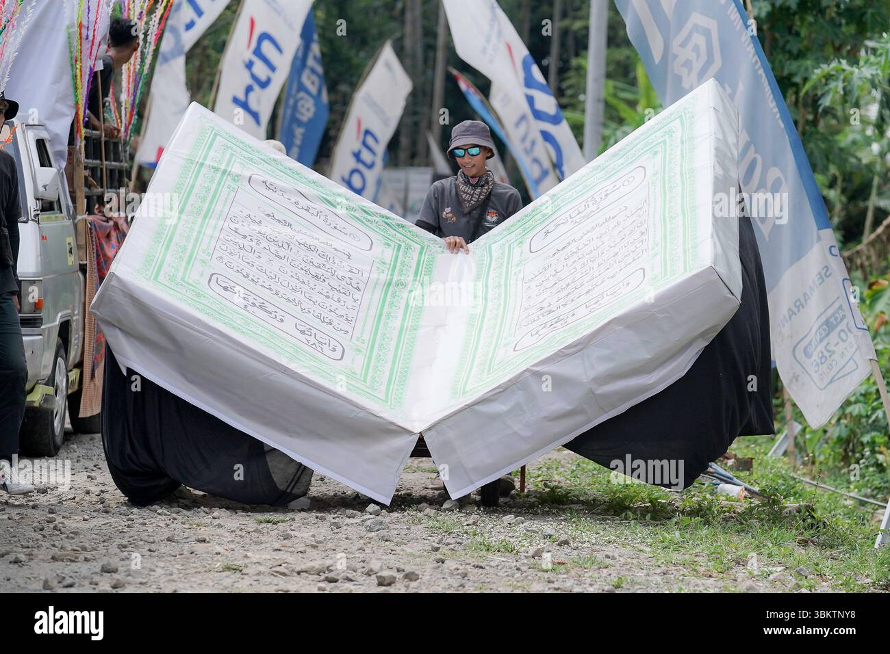 Un uomo mostra una gigantesca replica del Corano durante il Kirab Budaya. Parata culturale a Giava centrale, Indonesia, simboleggia la fede islamica e lui Foto Stock