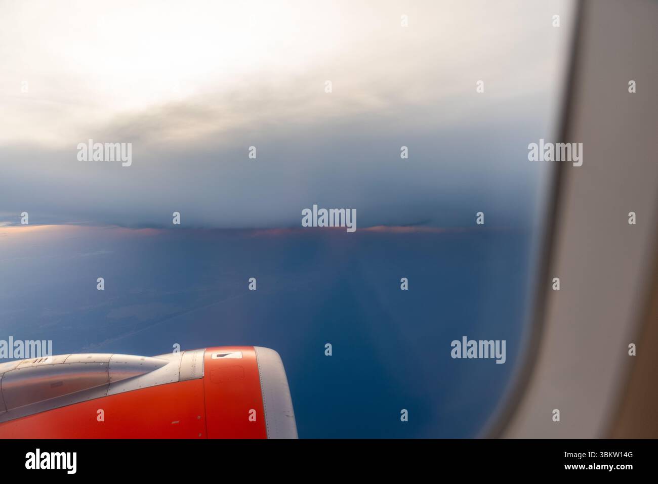 Vista di un tramonto sotto un forte banco nuvoloso dalla finestra di un aereo Airbus A320 easyJet sopra l'Europa. Andare in giro con il maltempo Foto Stock