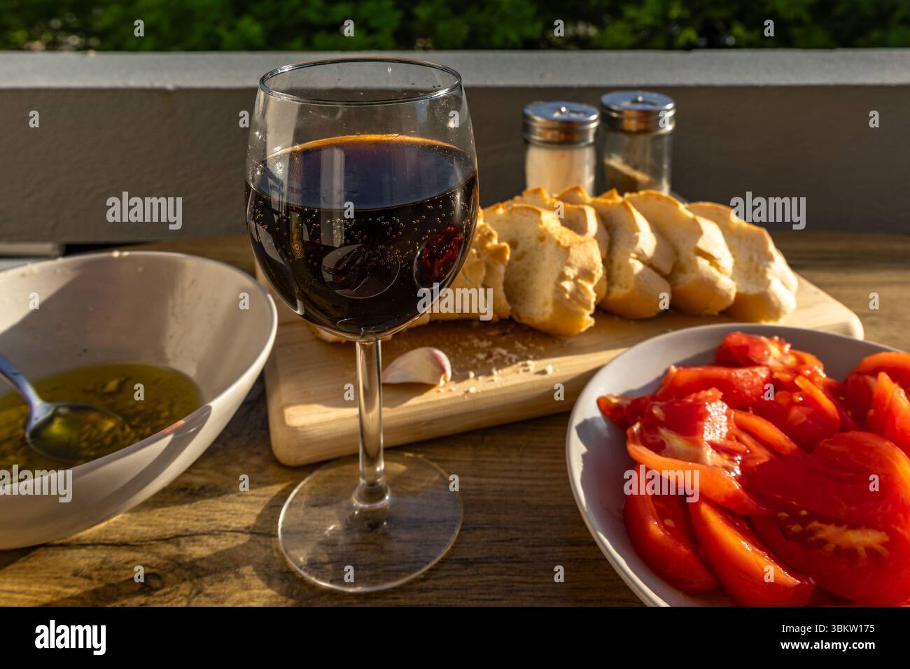 Bicchiere di vino, antipasto, vino rosso, cena, vino della Croazia, pomodori rossi, olio d'oliva, pane fresco, disposti su piatti su un tavolo in terrazza, Foto Stock