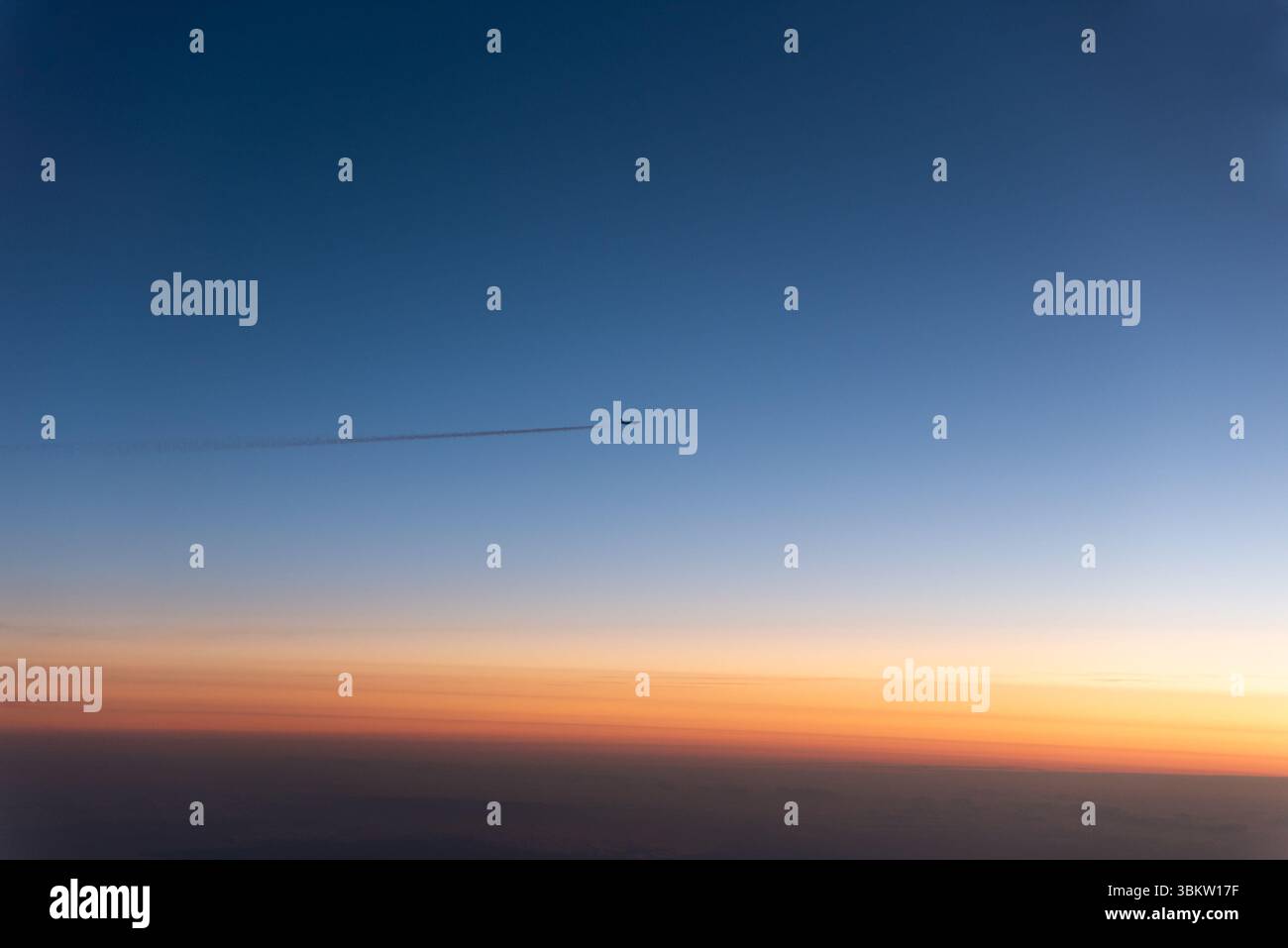 Vista di un tramonto dalla finestra di un aereo Airbus A320 easyJet sopra l'Europa, con un altro aereo di linea su un livello di volo simile che lascia un contrail Foto Stock