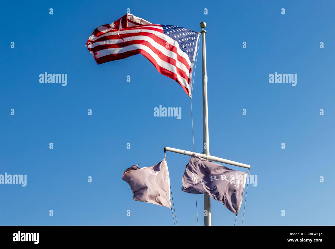 Asta di bandiera presso l'hotel Marram che sventola una bandiera americana e due bandiere di marram contro un cielo estivo blu Foto Stock