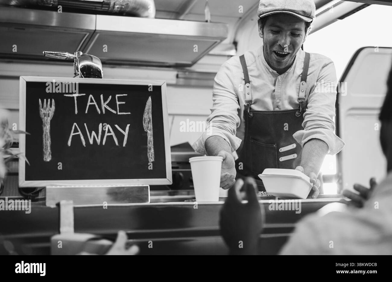 Le persone stanno aspettando fuori dal food truck mentre il giovane chef prepara la cena - concetto di pasto estivo e piccole imprese - concentrarsi sul volto dell'uomo-lavoratore Foto Stock
