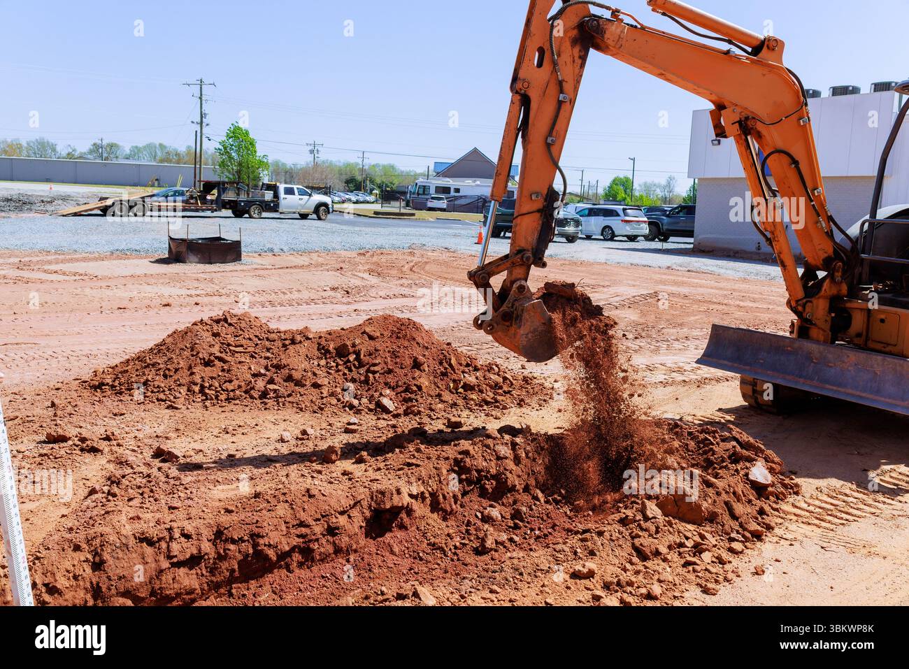 I macchinari pesanti scavano nel terreno, spostando il terreno rosso nel cantiere durante l'area di lavoro. Foto Stock