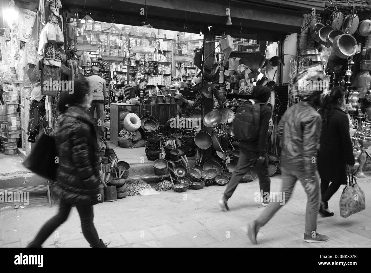 Pedoni e negozianti in un vivace mercato, con negozi che espongono pentole, gabbie per uccelli e merci a Thamel, Kathmandu, Nepal Foto Stock