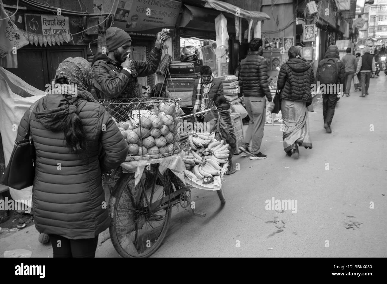Il venditore ambulante vende frutta dal suo carrello agli acquirenti in una vivace scena di mercato. Foto Stock