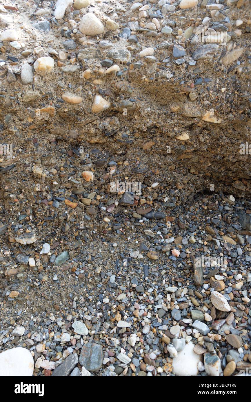 Banco di sedimenti esposto che mostra strati di rocce, ciottoli e sabbia. Foto Stock