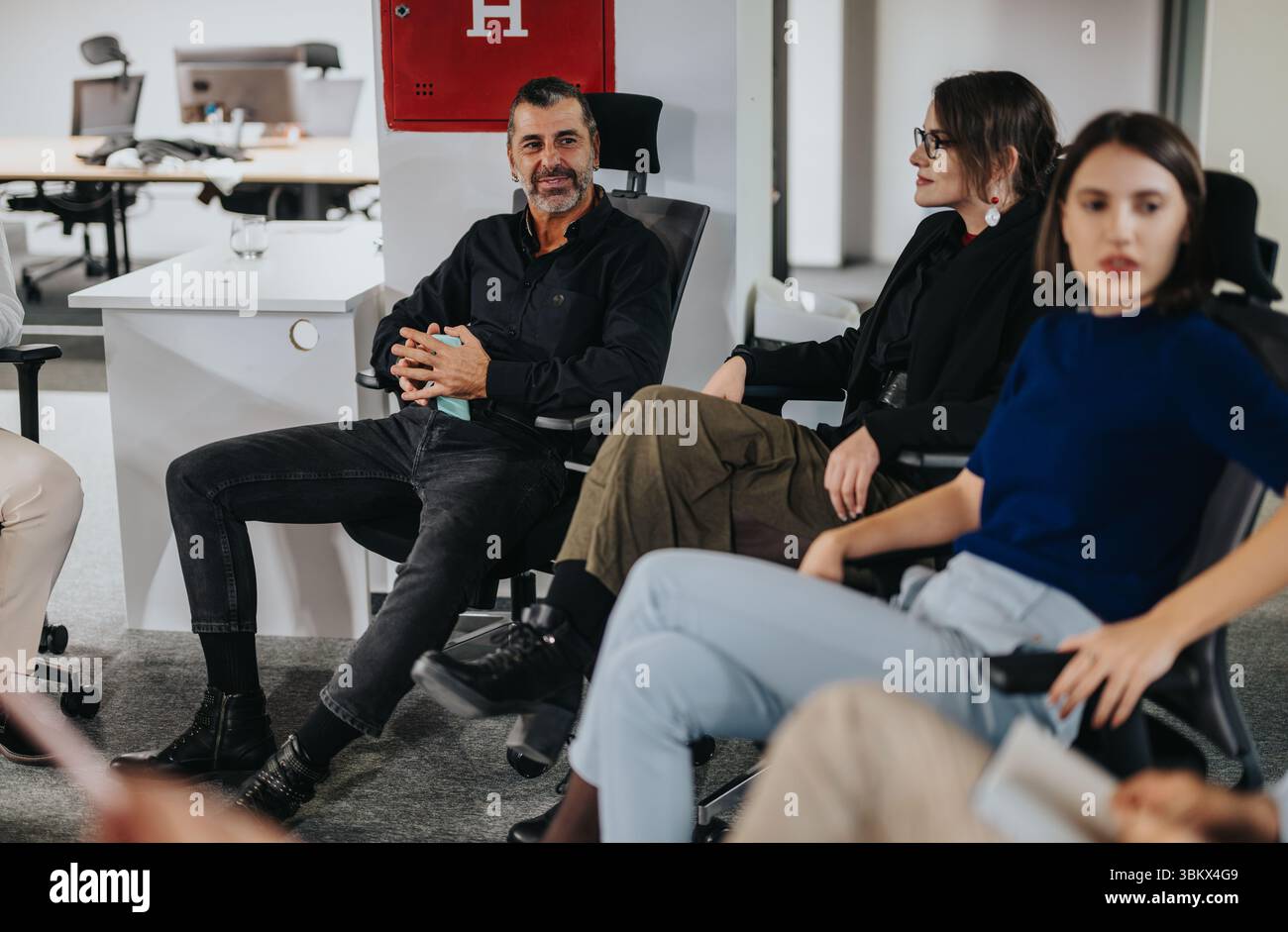 Il team aziendale è impegnato in vivaci discussioni in ufficio con un focus sul lavoro di squadra Foto Stock