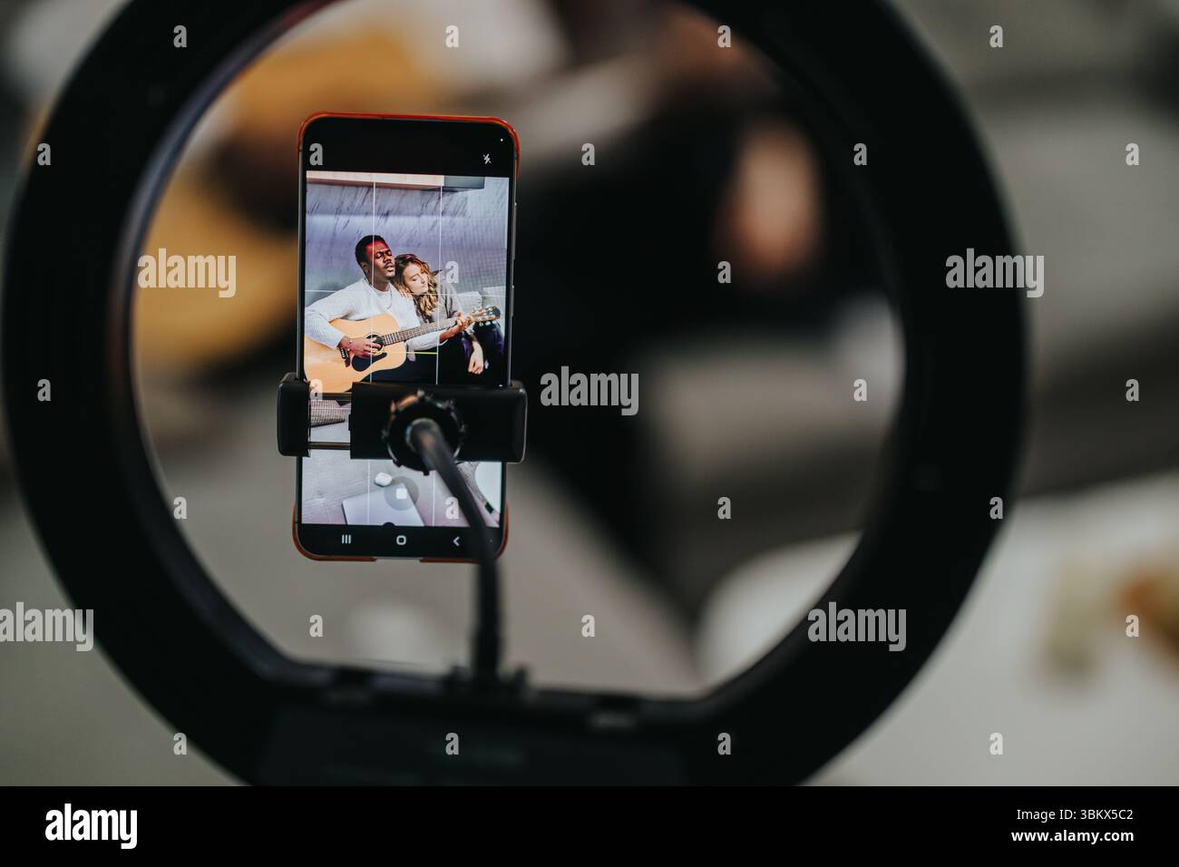 Esibizione di musica dal vivo catturata su smartphone con cornice illuminata che mostra musicisti che suonano la chitarra in un ambiente coinvolgente e vivace. Foto Stock