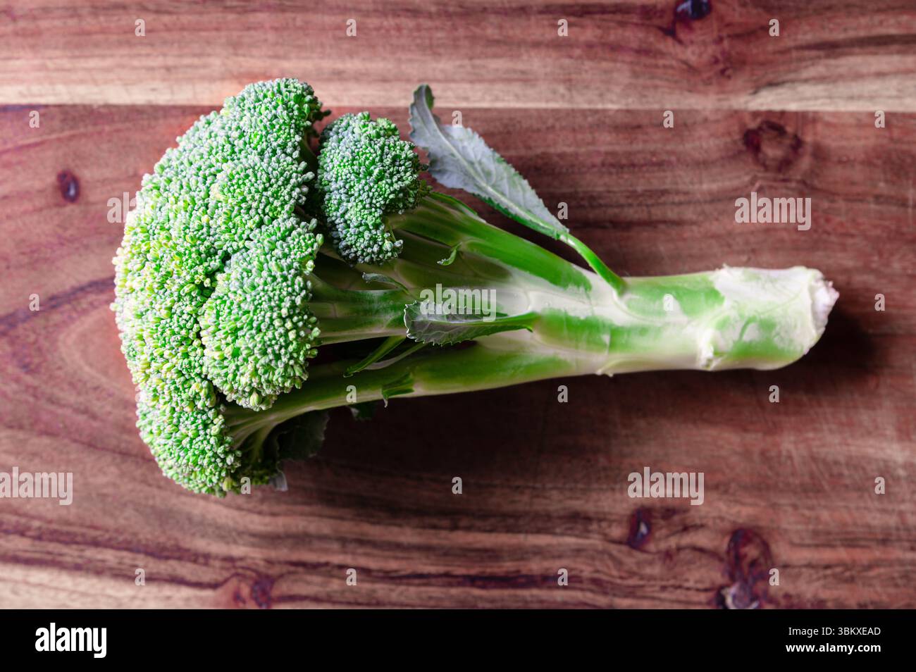 Una testa fresca di broccoli su un tagliere di legno Foto Stock