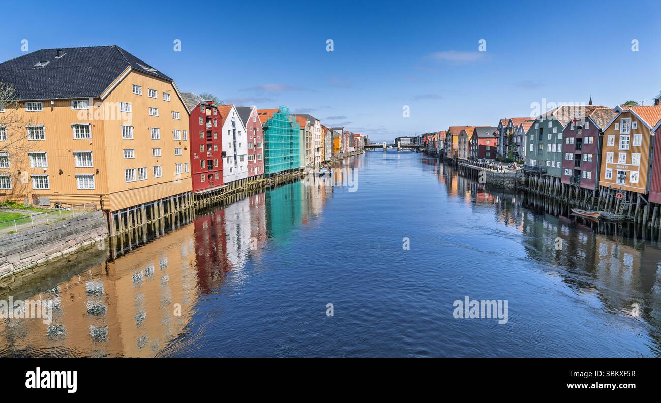 Splendida vista diurna di un tranquillo fiume fiancheggiato da colorati edifici storici sul lungomare sotto un cielo luminoso, con un pittoresco ponte e dist Foto Stock