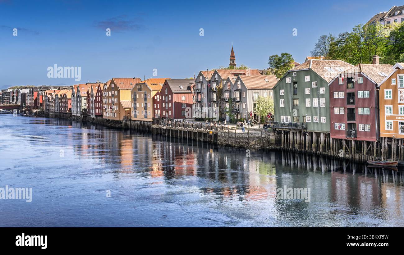 Splendida vista diurna di un tranquillo fiume fiancheggiato da colorati edifici storici sul lungomare sotto un cielo luminoso, con un pittoresco ponte e dist Foto Stock