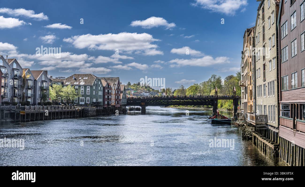 Splendida vista diurna di un tranquillo fiume fiancheggiato da colorati edifici storici sul lungomare sotto un cielo luminoso, con un pittoresco ponte e dist Foto Stock