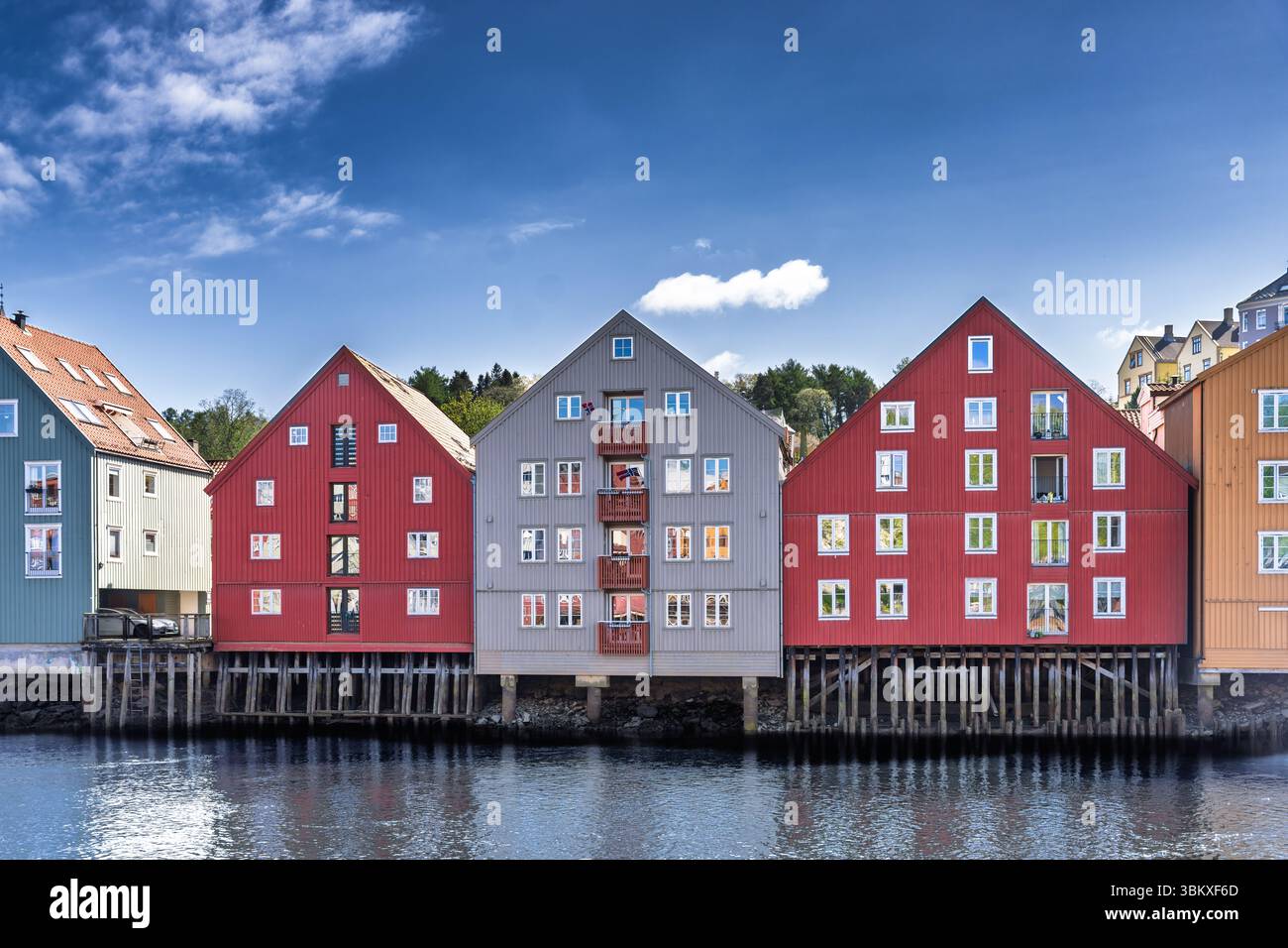 Splendida vista diurna di un tranquillo fiume fiancheggiato da colorati edifici storici sul lungomare sotto un cielo luminoso, con un pittoresco ponte e dist Foto Stock