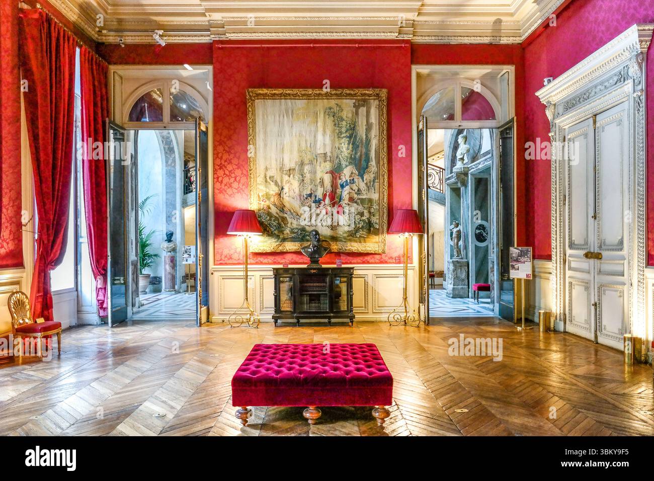 Gli sfarzosi interni rossi del salone Museum Jacquemart-André Paris presentano arredi dorati ornati, lampadari di cristallo e pavimenti in parquet a spina di pesce Foto Stock