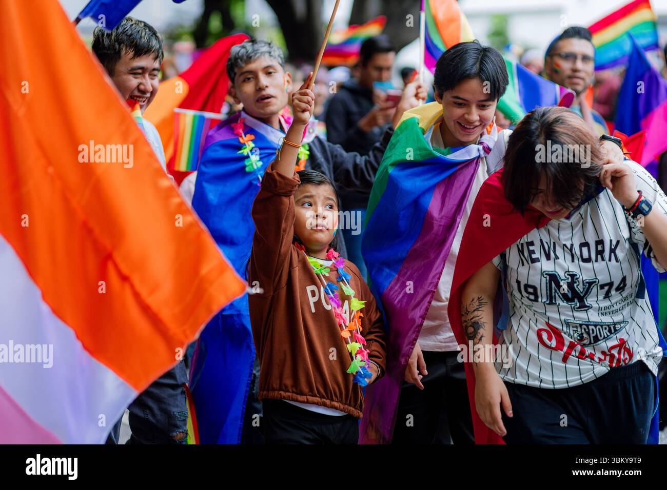 I bambini in costume colorato con bandiera arcobaleno celebrano l'orgoglio LGBTQ+ insieme agli adulti in una sfilata all'aperto inclusa. Foto Stock