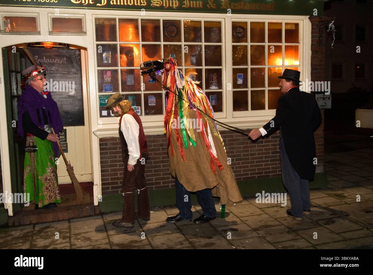 Hooden Horse, Sandgate, Kent. Hoodening una tradizione natalizia tipica dell'isola di Thanet nel Kent. Gli Hoodener visitano una varietà di pub a Sandgate, la figura hobby del cavallo era tradizionalmente accompagnata da una Mollie, una figura uomo-donna, che aveva superato il suo primo posto, e che percorreva il sentiero con una tradizionale scopa besom. Il Waggoner e il ragazzo in un berretto piatto. Stiamo per entrare nello Ship Inn. Sandgate, Kent, Inghilterra 21 dicembre 2012 UK 2010s HOMER SYKES Foto Stock