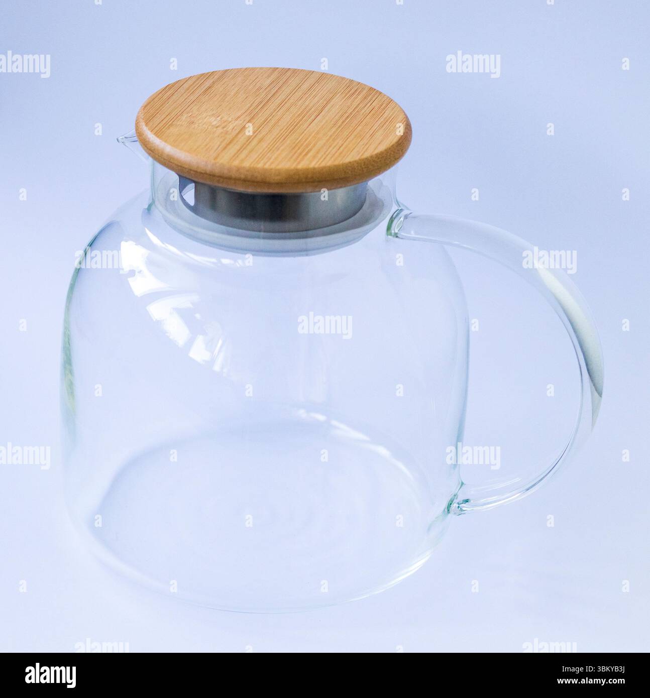 Elegante teiera trasparente con coperchio in legno su sfondo bianco Foto Stock