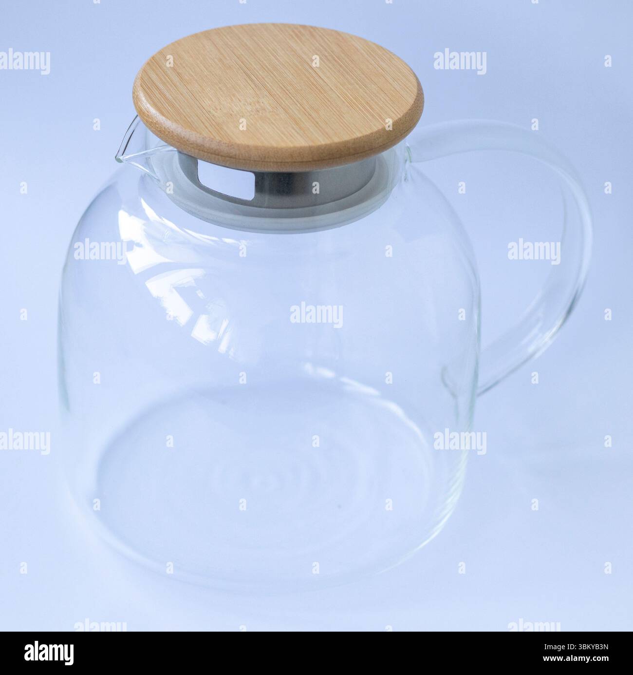 Elegante teiera trasparente con coperchio in legno su sfondo bianco Foto Stock